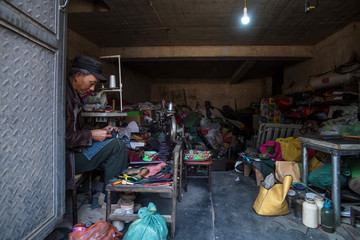 A Cobbler sewing a shoe at his workshop