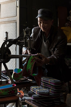 A Cobbler sewing a shoe at his workshop