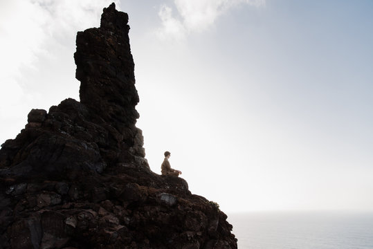 Woman sitting in lotus pose on high mountain.