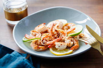 Fried tiger shrimp with lime, lemon and spices on a ceramic dish. Healthy dinner or lunch concept.