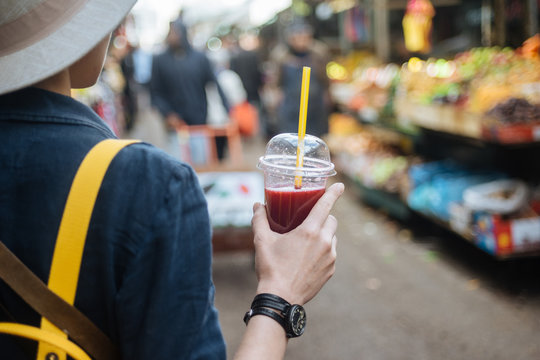 Woman with shake in cup walking on street