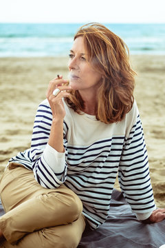 Portrait of a attractive woman of fifty years smoking at the beach