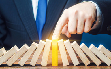 Businessman with a touch stops process of falling dominoes. Successful strong business, solve all...