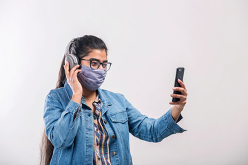 A teenager girl with mask enjoying music while quarantine during covid-19 pandemic