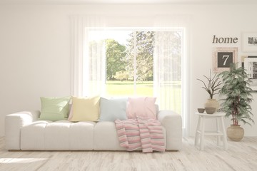 White living room with sofa and summer landscape in window. Scandinavian interior design. 3D illustration