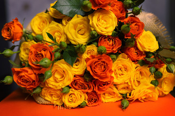 A beautiful, bright bouquet of orange and yellow small flowers-roses on an orange background, close-up, copying the space.