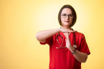 Beautiful woman doctor with stethoscope, wearing red scrubs showing time out gesture