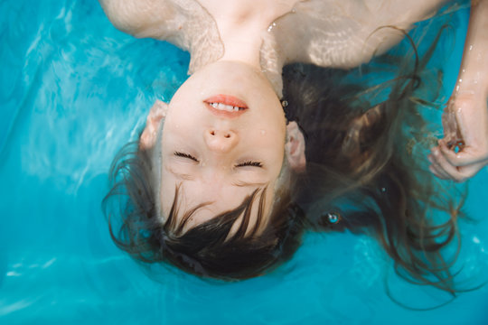 Portrait of a little girl in the water with closed eyes