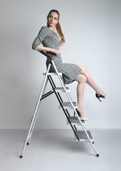 Smiling businesswoman sitting on career ladder on white wall background