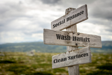 Signpost outdoors with the text social distance, wash hands and clean surfaces to illustrate three basic rules for people to follow during the global pandemic of coronavirus or Covid-19 epidemic.