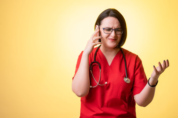 Beautiful woman doctor with stethoscope, wearing red scrubs displeased face and gestures and...
