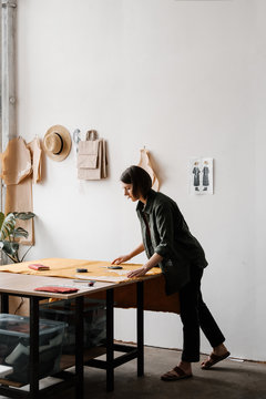 Female dressmaker drawing and measuring.