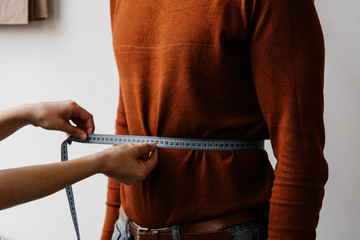 Seamstress doing measure of male waist by centimeter tape