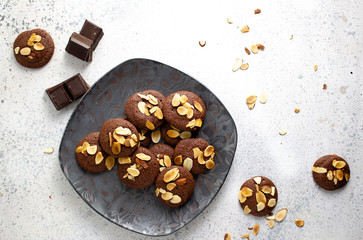 Plate of almond brownie cookies with scattered flaked almonds and chinks of chocolate