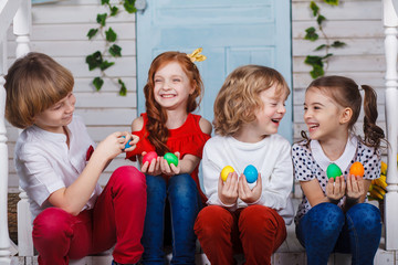 Children holding easter eggs. Beautiful children sit near the basket with tulips and hold Easter eggs in their hands. Funny moments