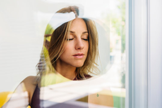 Portrait of concentrated young woman doing yoga postures behind a window
