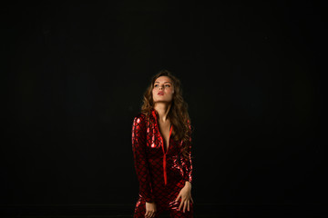 sexy girl posing in a red suit on a black background