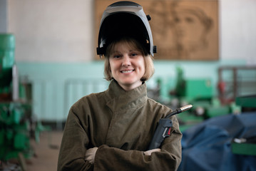 Woman welder with a welding torch in her hands.
