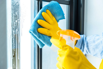 Wife housekeeping and cleaning concept, Happy young woman wiping dust using a spray and a duster while cleaning in glass at home
