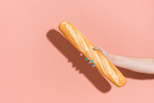 Hand holding a baguette.