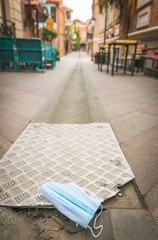 Obraz na płótnie Canvas Blue mdeical face mask on the ground in empty street of Ghost town Tbilisi during corona virus pandemic. Concept of medical supplies. 25.03.2020.