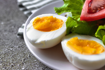 Eggs on the plate. Hard boiled eggs cut in half with tomato and lettuce in close up for healthy breakfast