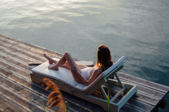 Woman sunbathing on deck chair on the riverside
