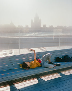 Stylish girl lying on a bench and taking selfie photo with a smarphone
