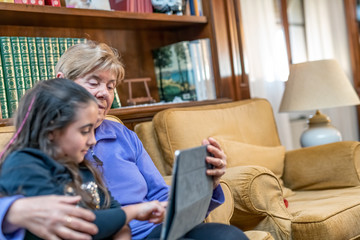Young girl learning at home with her grandmother in coronavirus times