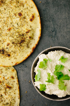 Spiced flatbread with hummus on side with coriander