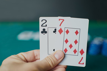 Bad poker gamble or unlucky hand concept with player going all in with 2 and 7 (two and seven)...