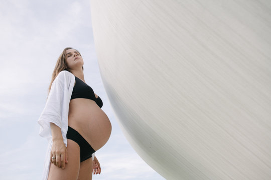 Pregnant Woman Stands By Sphere