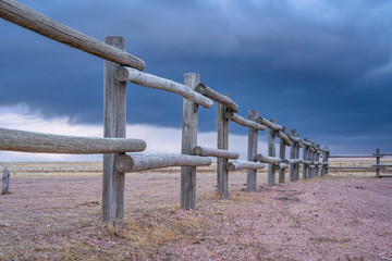 wooden fence and dark stormy sky in prairie