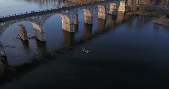 Drone small fishing boat sailing under train crossing 