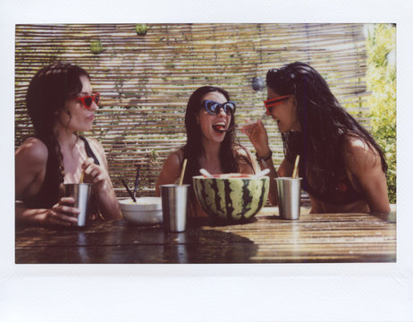 Polaroid photo of tree funny girls eating watermelon.