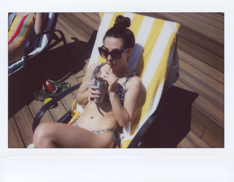 Polaroid photo of woman relaxing and drinking cocktail.
