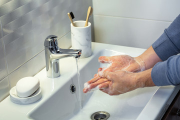 A man use soap and washing hands under the water tap.