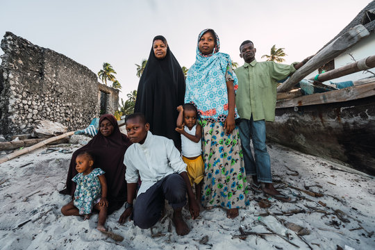 Portrait- Muslim zanzibari family, adults and children posing on the white sand.