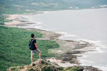 Man looking at the sea from stony coast