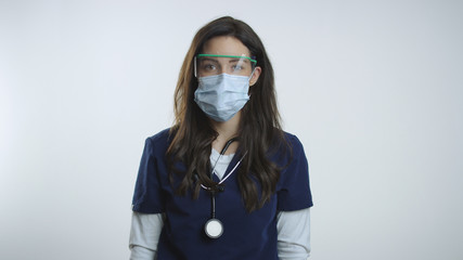 Nurse wears protective goggles and mask as she looks to camera