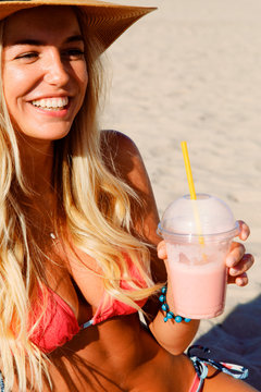 Cheerful woman with milkshake relaxing on beach