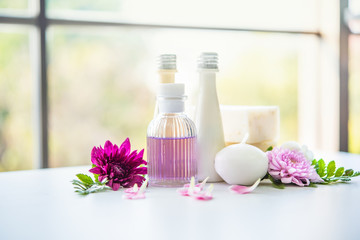 Spa setting. purple oil in bottle, towels and flowers on white table. Selective focus. Place for text.