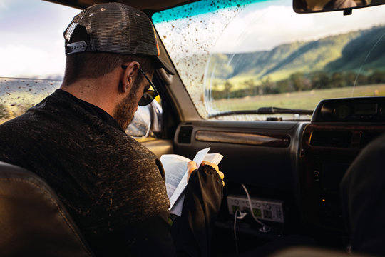 Passenger reviews his travel guide inside the car. Safari day in
