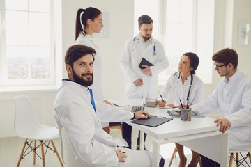 Obraz premium Portrait of a practicing doctor on the background of collegues in the clinic office.