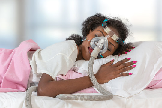 Woman wearing CPAP headgear to sleep against apnea