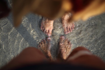 The feet of two people who soak in the beach