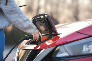 Woman is plugging electric vehicle for charging car battery at parking. Close up. Plugged charging...
