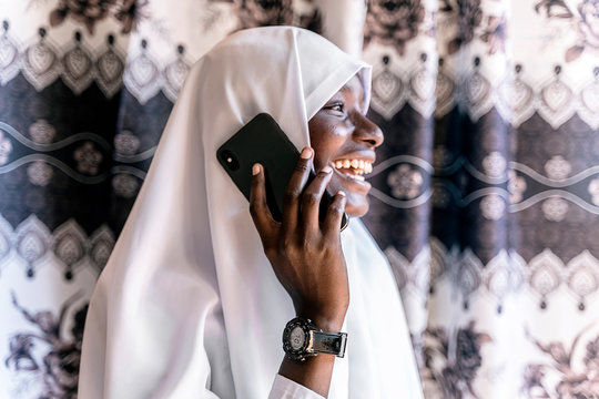 Young African Muslim wearing a white hijab using her mobile phon