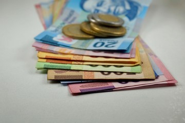 Many mexican pesos bills with coins on top spread over a surface