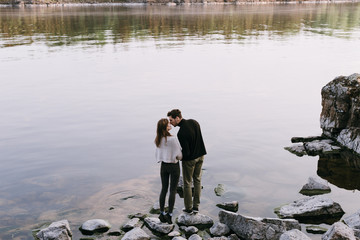 Romantic couple holding hands and kissing standing on lake shore